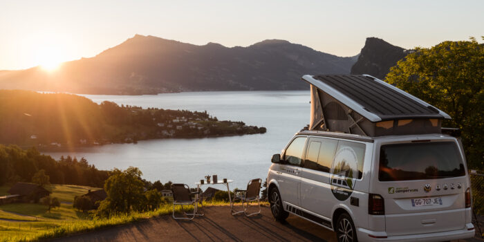 Van Volkswagen California garé au bord d'un lac lors d'un couché de soleil